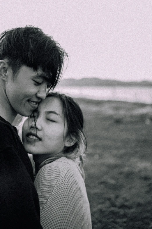 a young couple standing close together in the grass