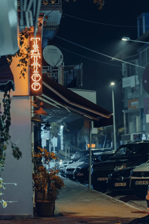 a street corner with cars and neon sign