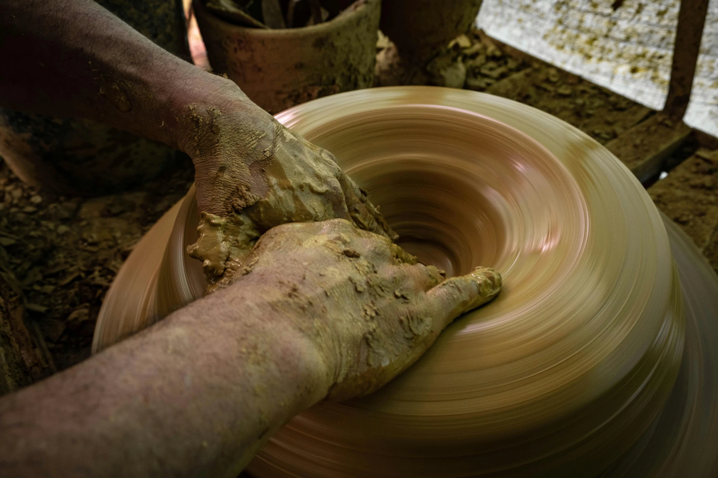 a potter is kneading his pottery wheel with his hands