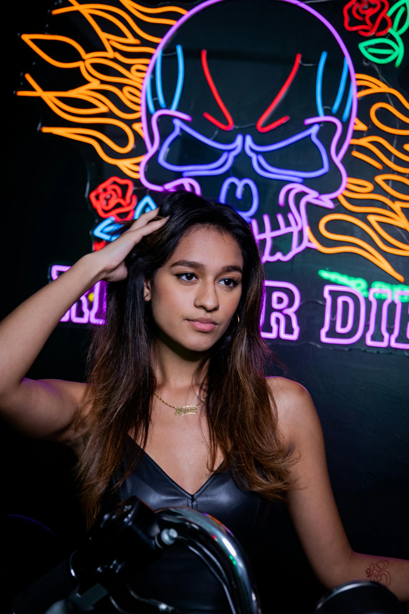 a beautiful young lady sitting under neon lights