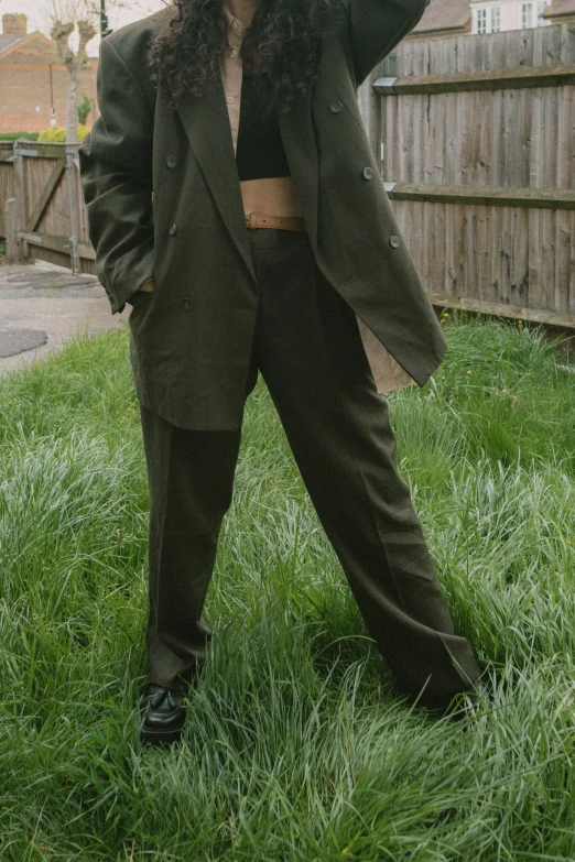 a woman with long curly hair is standing in grass