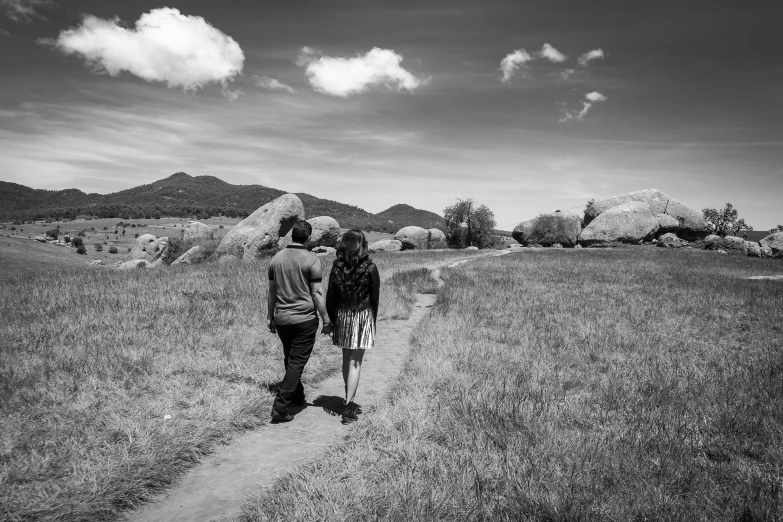 two people walking on a trail in a field