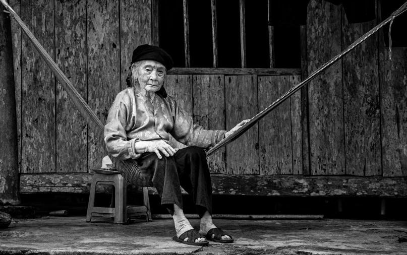 a man sits on a bench outside of an old wooden house