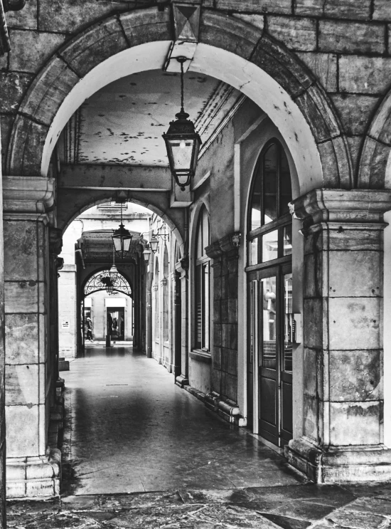 an arched walkway between a building with many windows and doors