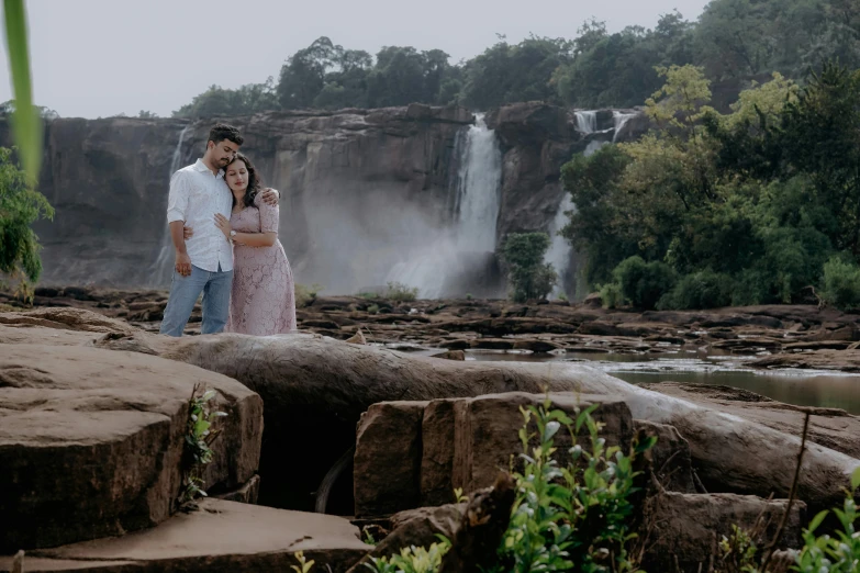 two people stand in front of the water fall