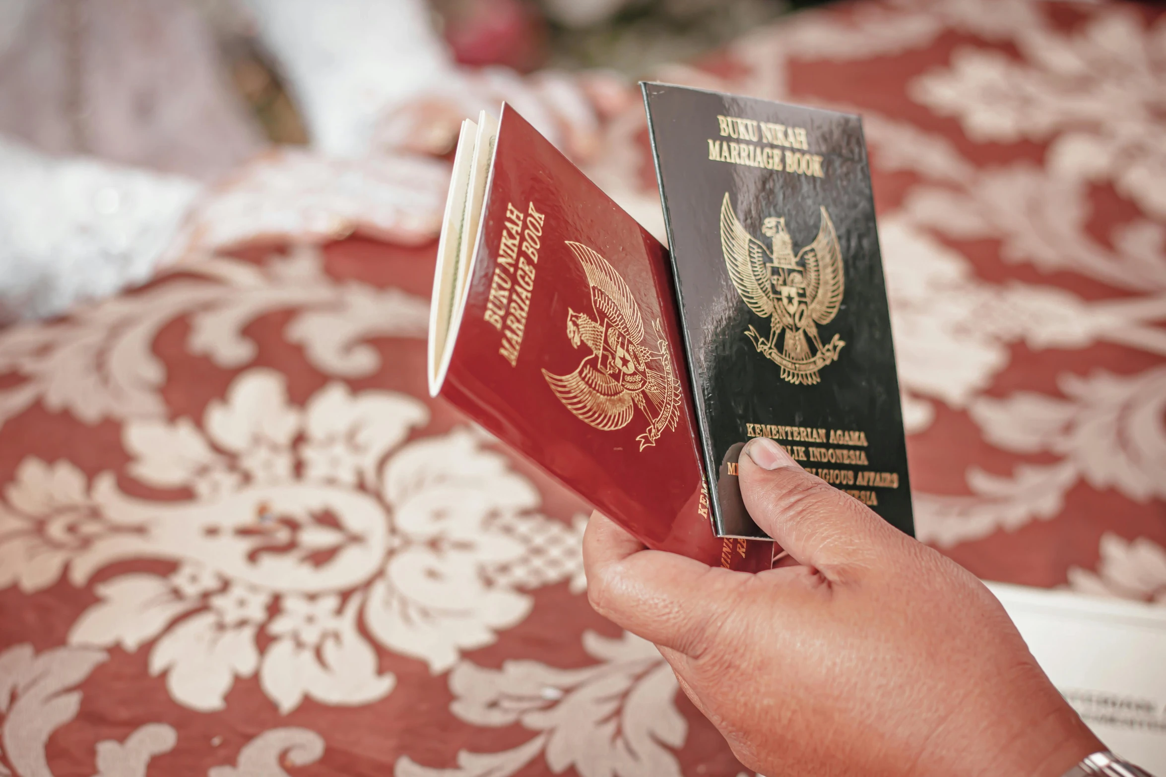 two passports are in their hands in front of a red table