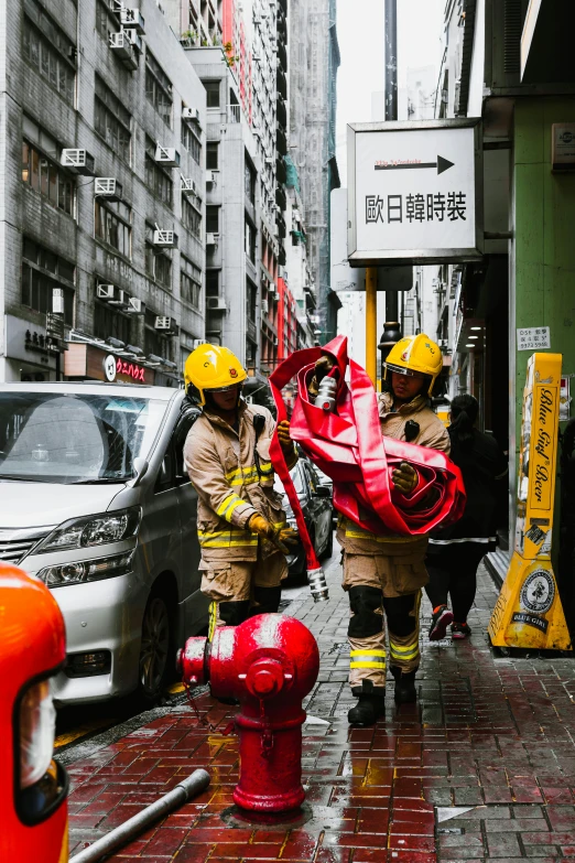 firefighters put out a fire hose and water hydrant on a rainy street