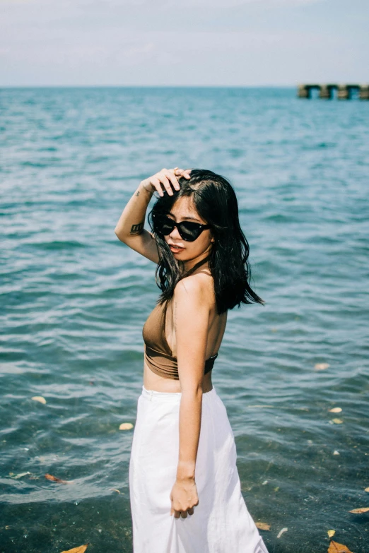 an asian woman stands on the edge of the water