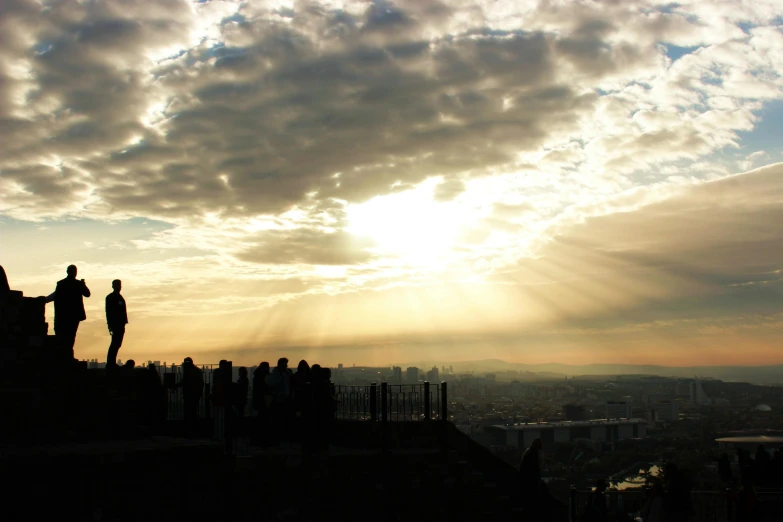 people standing on a hill while the sun is shining down