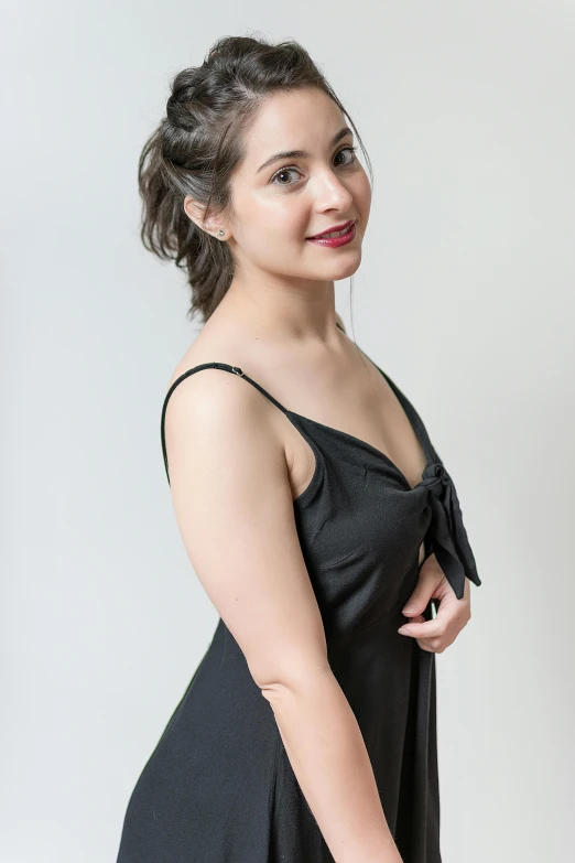 a young woman wearing a black dress standing with her hands on the hips