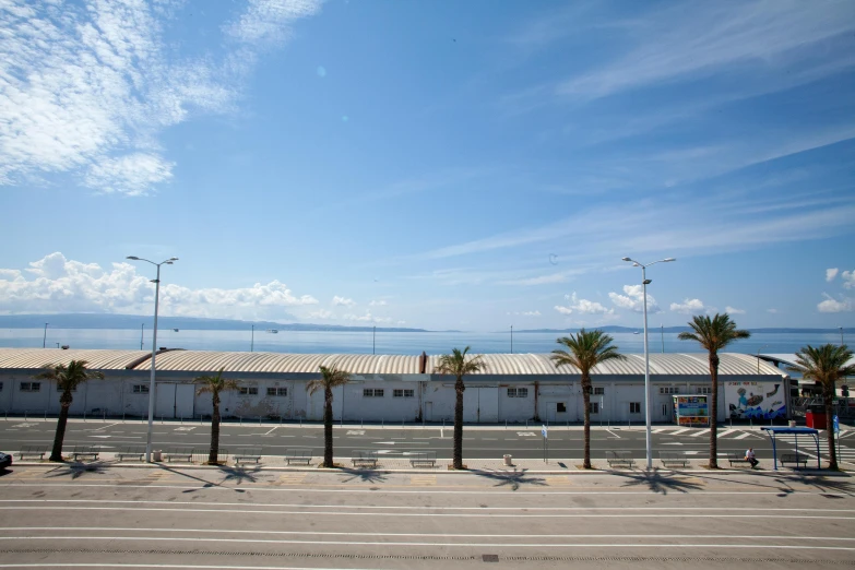 an empty parking lot has a fence and a building in the background