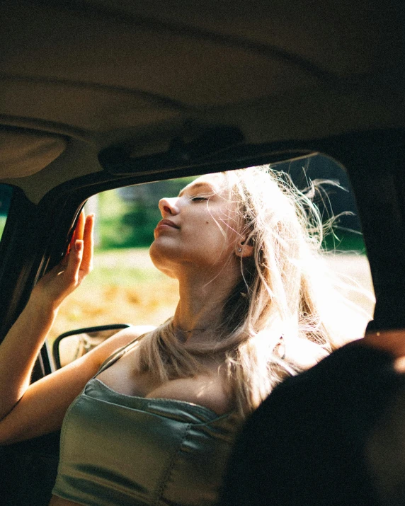 woman in the back seat of a car, holding her head up to her window