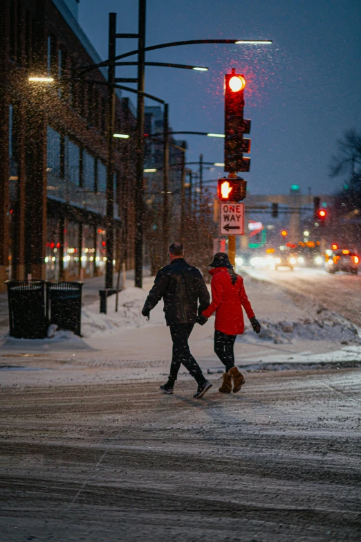 two people walking down a street covered in snow