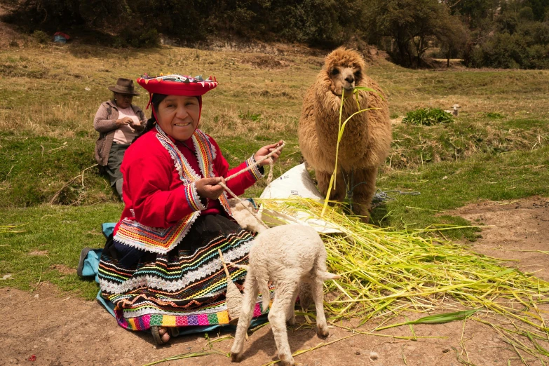 the woman in the mexican costume is showing her goat some grass