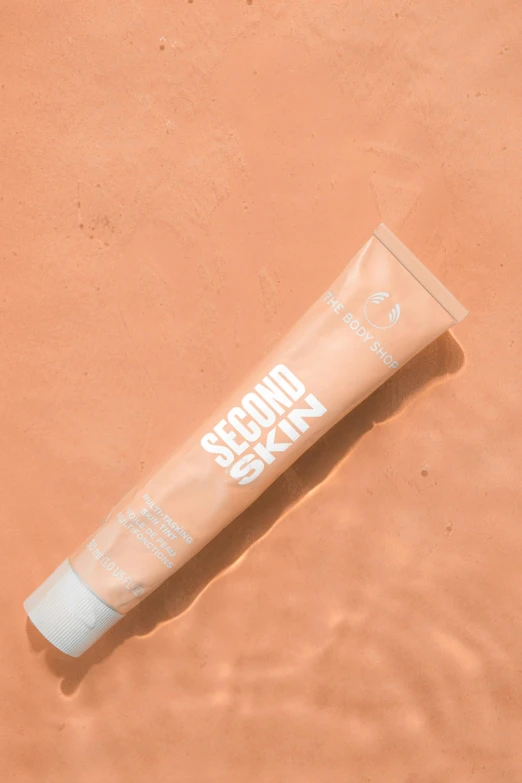 sunscreen tube resting on sandy surface by edge