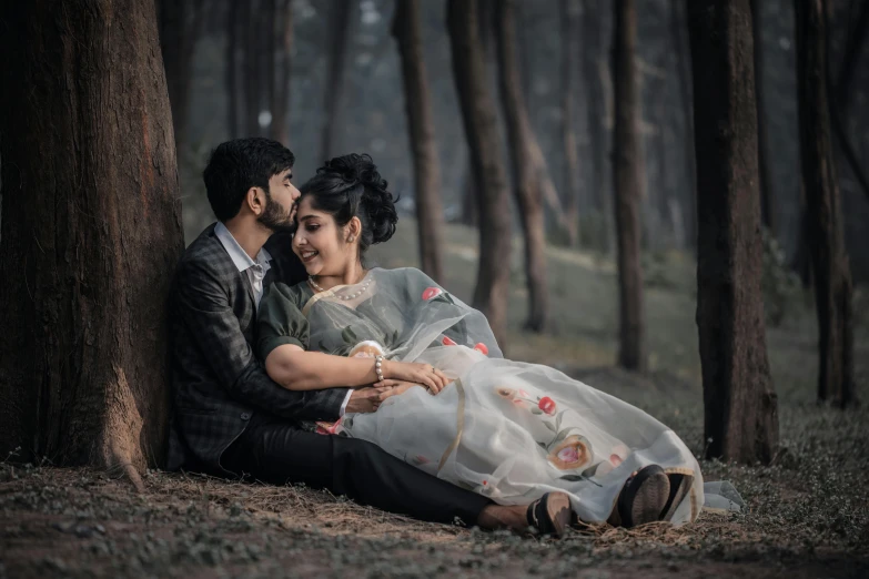 the young couple are posing by the trees