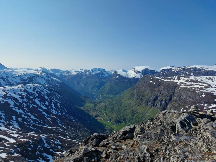 a mountain range with snow covered mountains and green vegetation