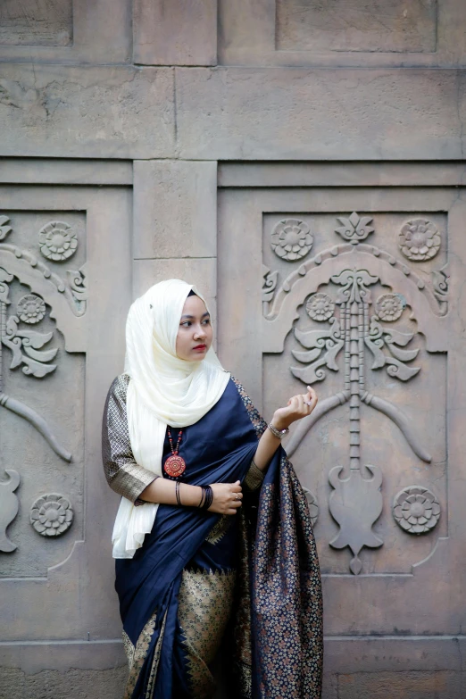 woman in dress leaning on a brick wall