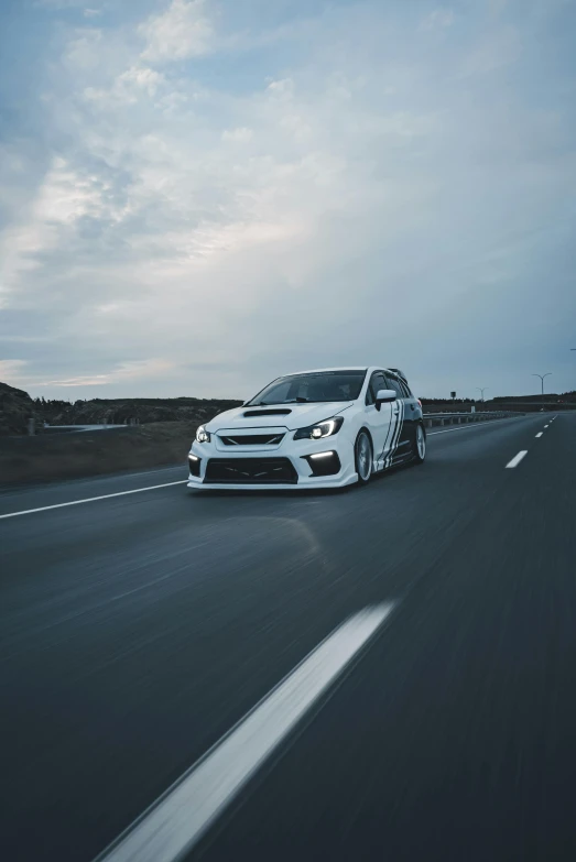 a white car driving on the highway next to a field