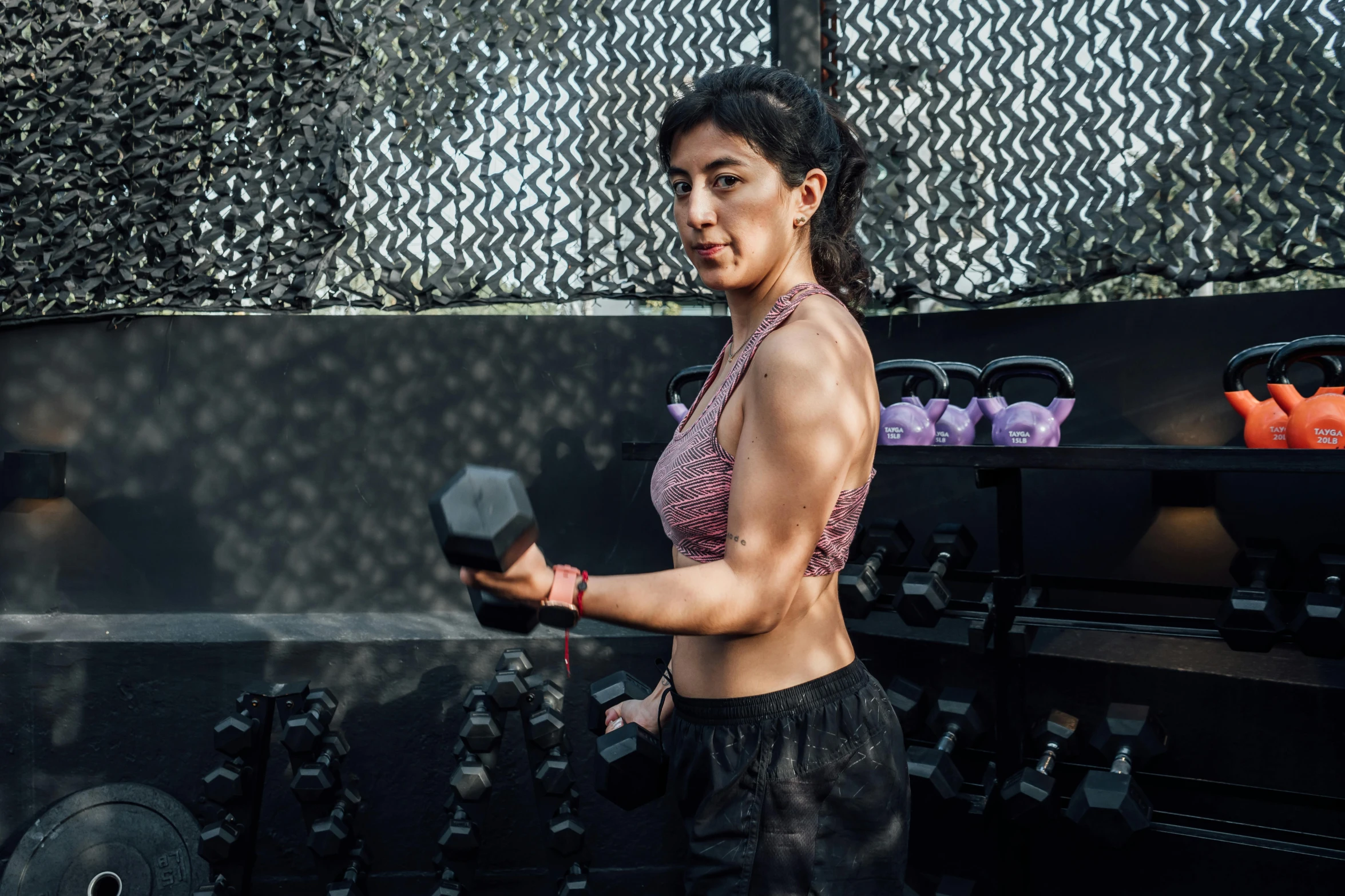 a woman is lifting a weights bar while posing for the camera