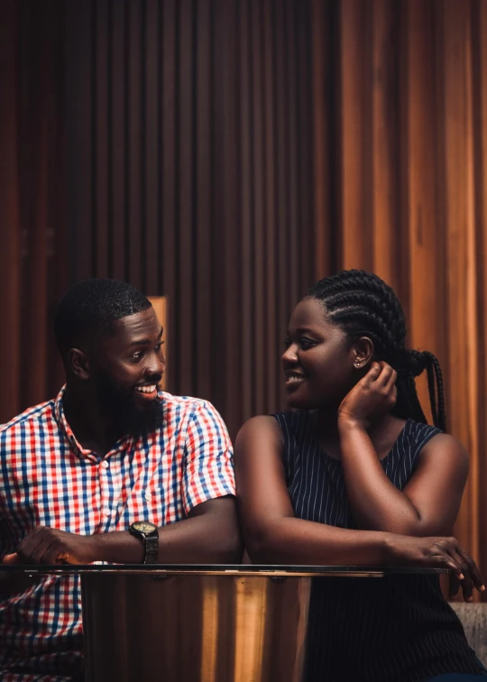 a man and a woman are sitting together, one looks at the camera,