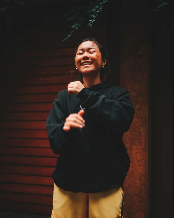 a woman standing in front of a building smiling and waving her arms