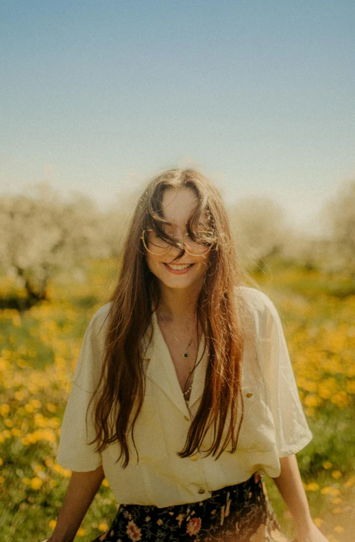a smiling woman standing in a field with wild flowers