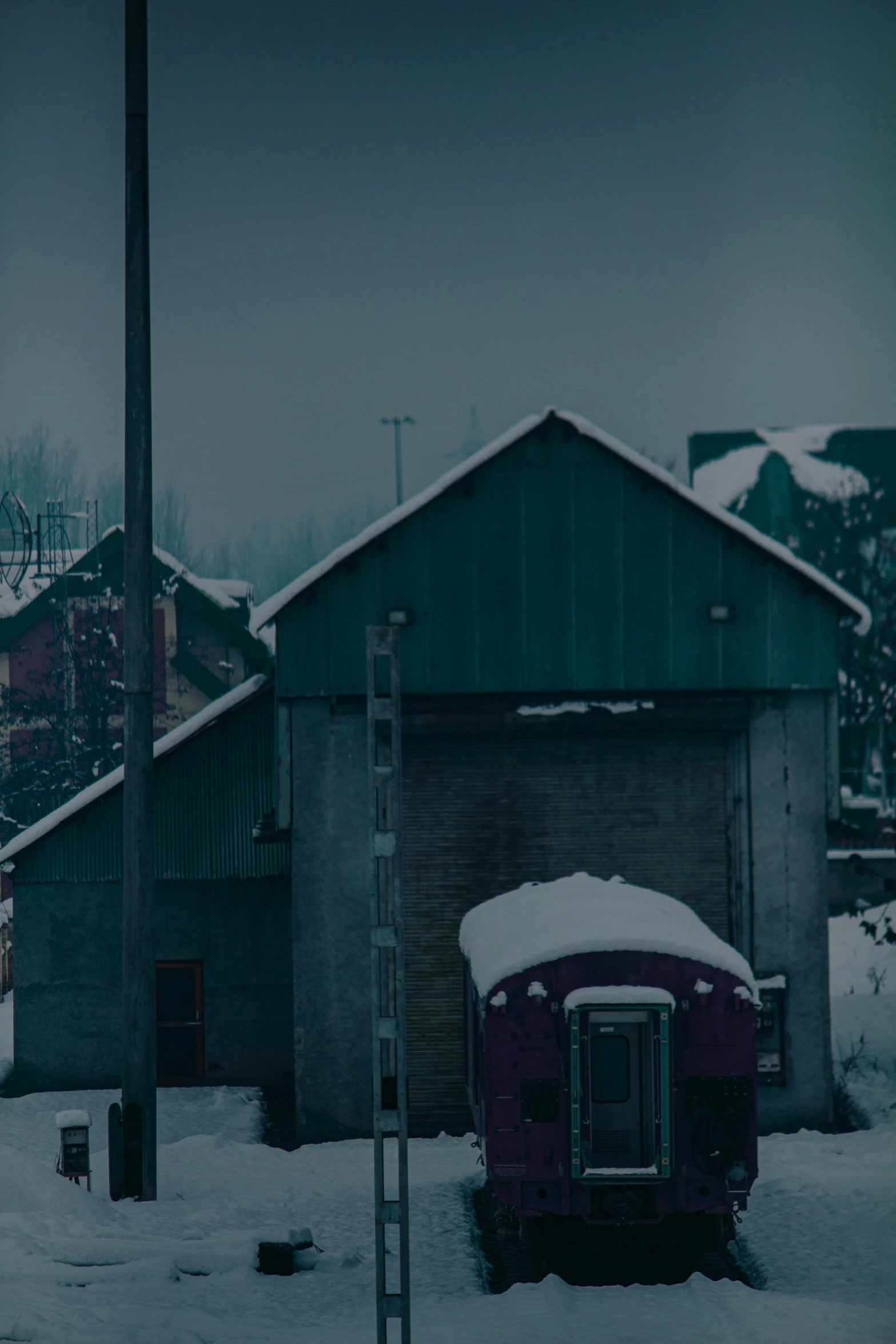 a snow covered road with a train near some houses