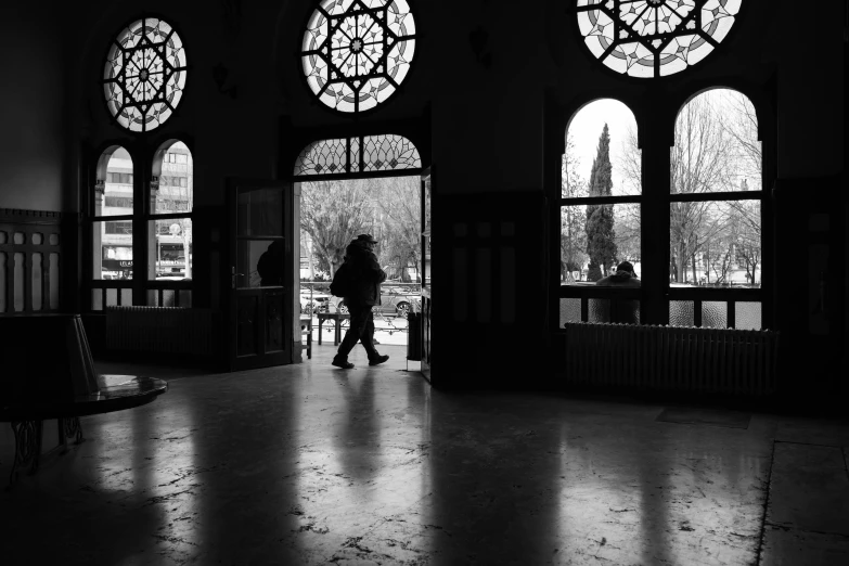 a person standing inside a building, some windows lit by sunlight