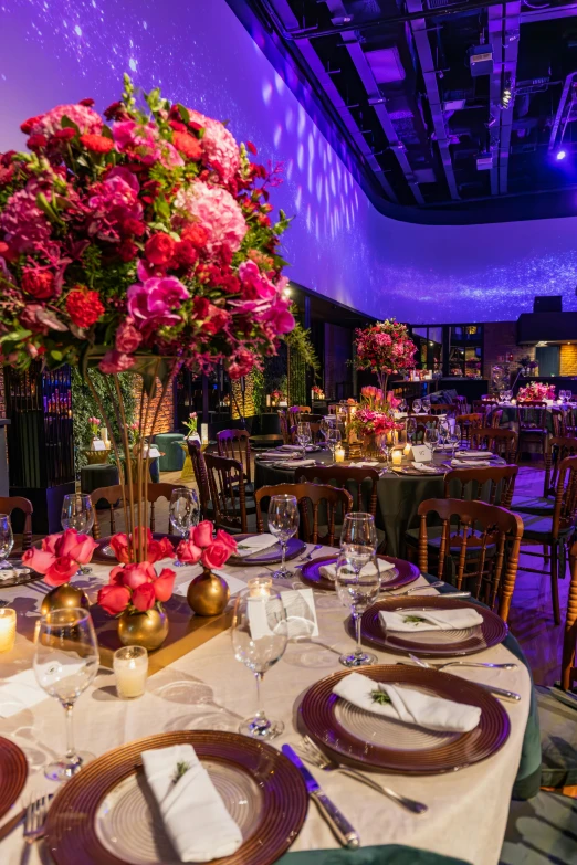 the banquet tables are set for dinner, the centerpiece is a vase filled with flowers