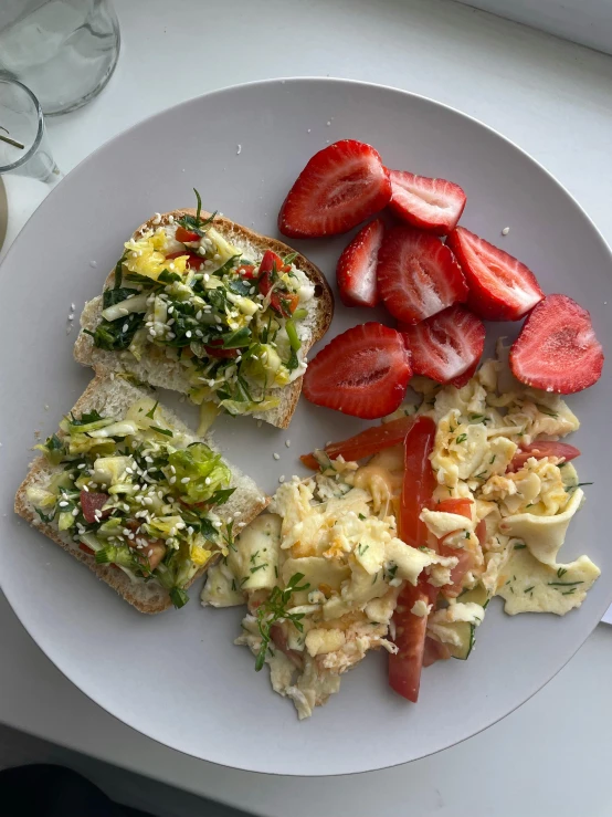 the plate contains slices of toast and sliced up strawberries