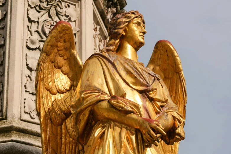 the golden angel statue is at the base of the stone building