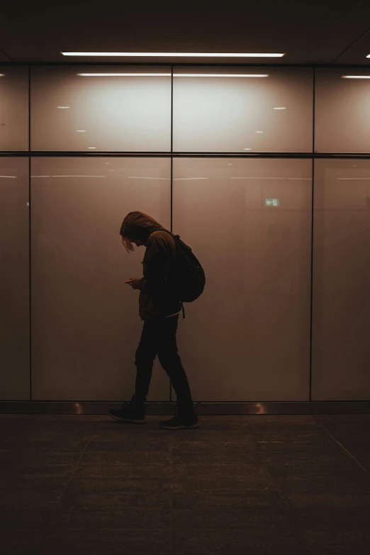 a person walking by a glass wall and cell phone