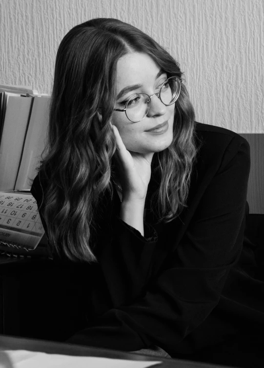 a woman with glasses sitting at her desk