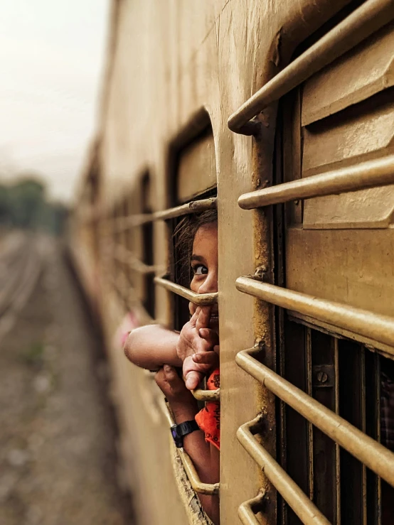 there is a girl looking out the window of a passenger train