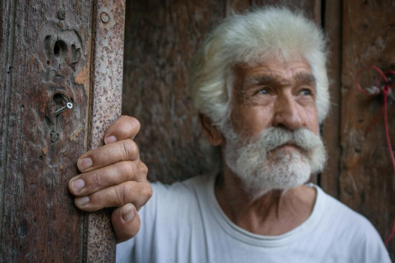 a man with long gray hair and white beard holds a board