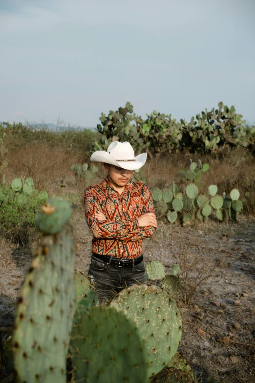 a man is standing in the middle of the desert wearing a cowboy hat