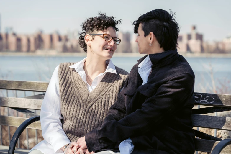 an older woman and young man sitting on a park bench facing each other