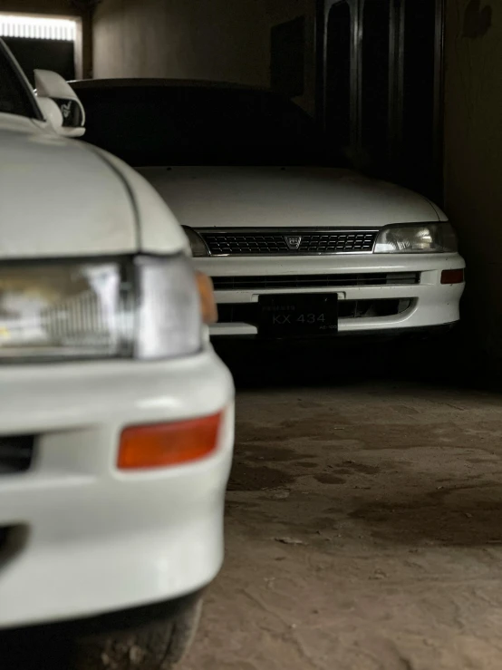 two cars in the garage, one has it's hood up