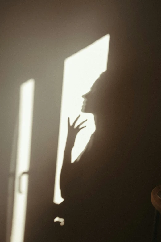 a silhouetted person with their hands out of the window