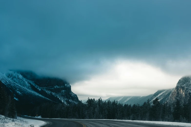 an empty road and snowy mountains in the distance