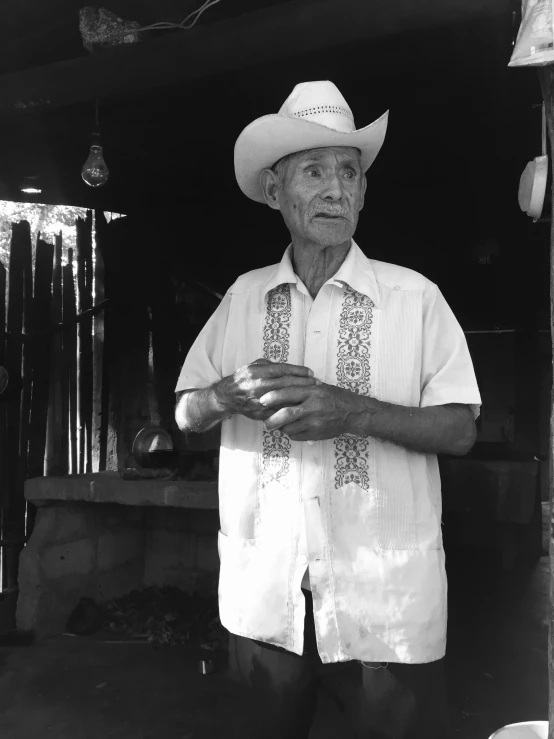 man in white shirt holding a cup and wearing cowboy hat