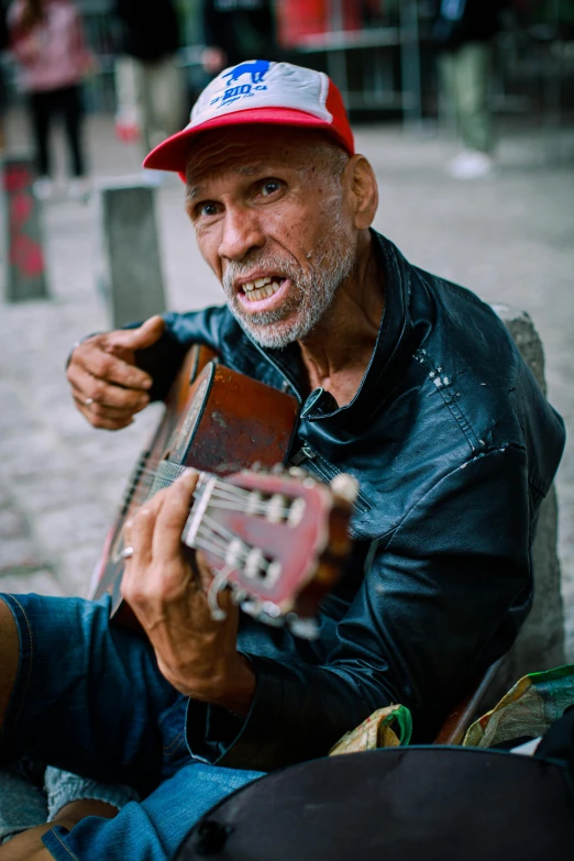 a man with a red hat playing a guitar