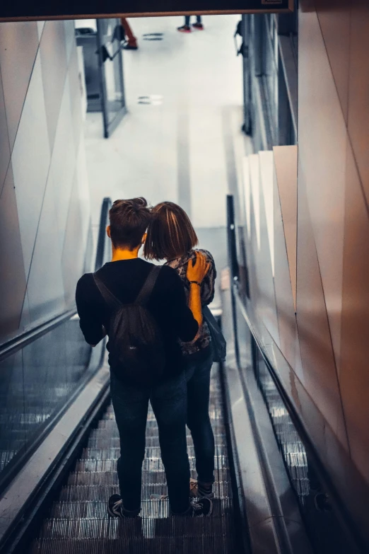 two people walking up the escalator in the rain