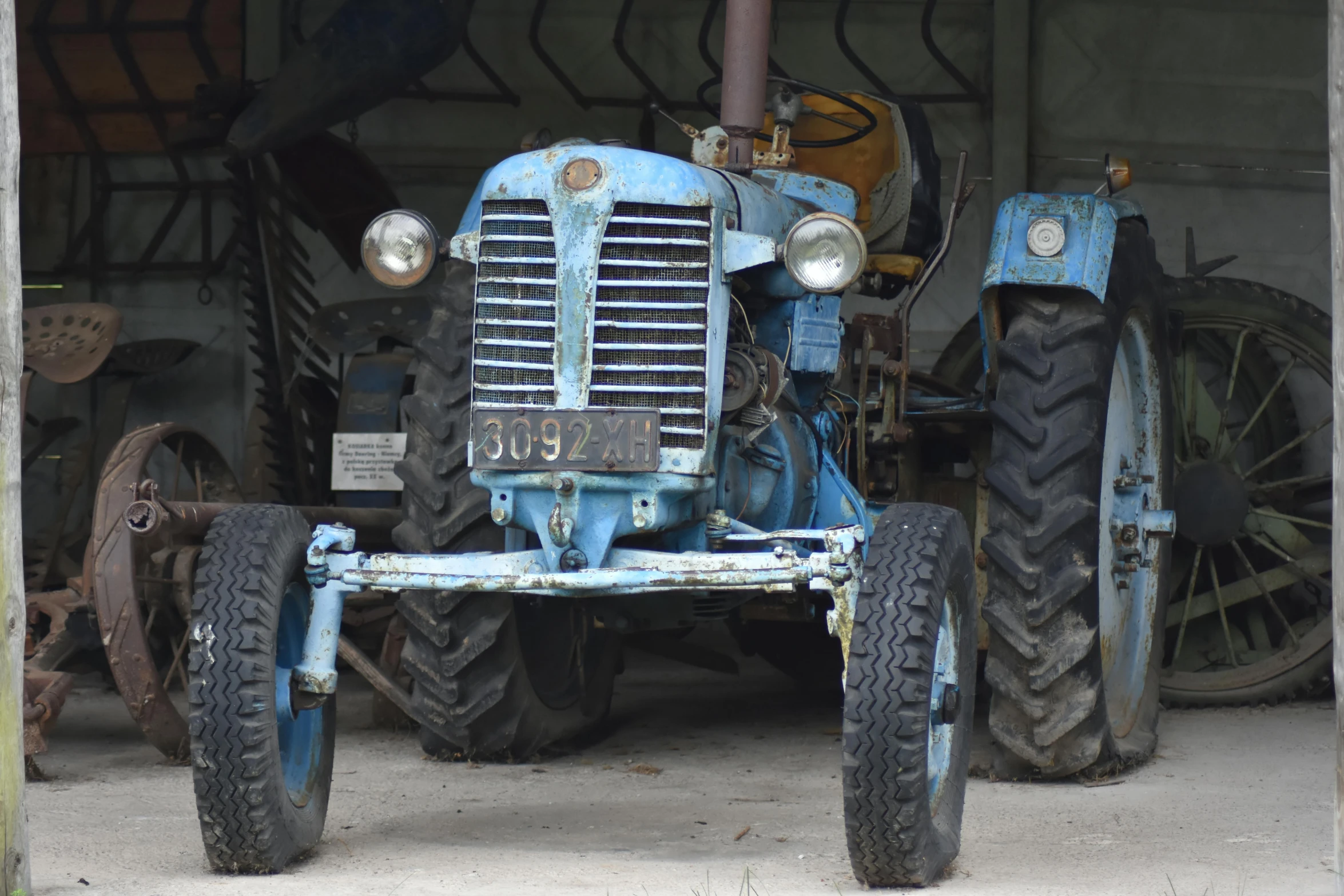 there is an older blue farm tractor in the garage