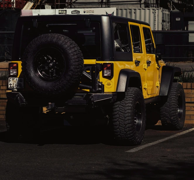 a yellow jeep with its large black tires is parked on a parking lot