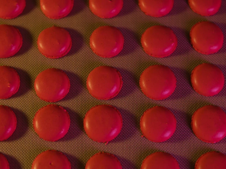 a baking tray filled with red frosted cookies