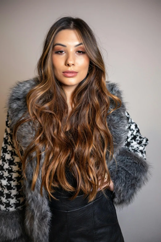 a woman posing in a grey sweater and fur coat