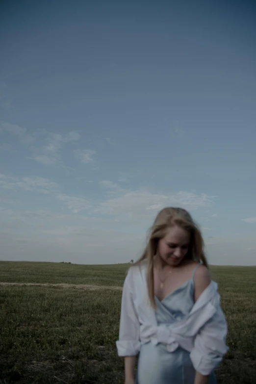 a woman standing in a field with a kite overhead