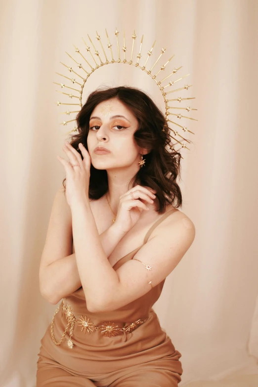 a woman in a tan bathingsuit is looking upward and wearing an old - school gold crown